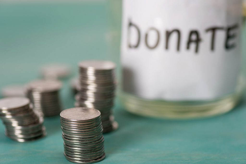 close-up view of stacked coins and glass jar for donate, donation concept